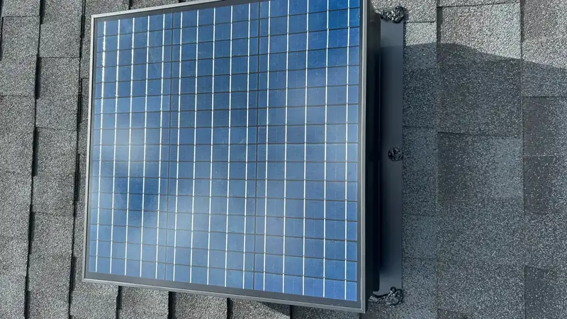 Solar attic fan mounted on a shingle roof, photographed from above
