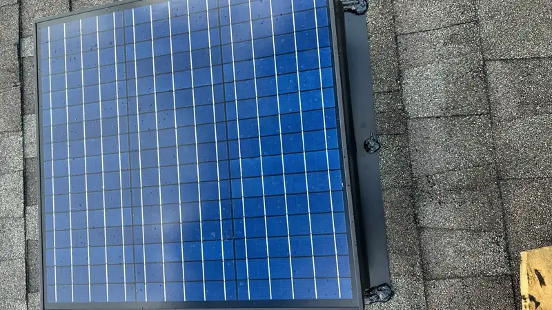 Solar attic fan with its panel angled toward the sun on a residential roof
